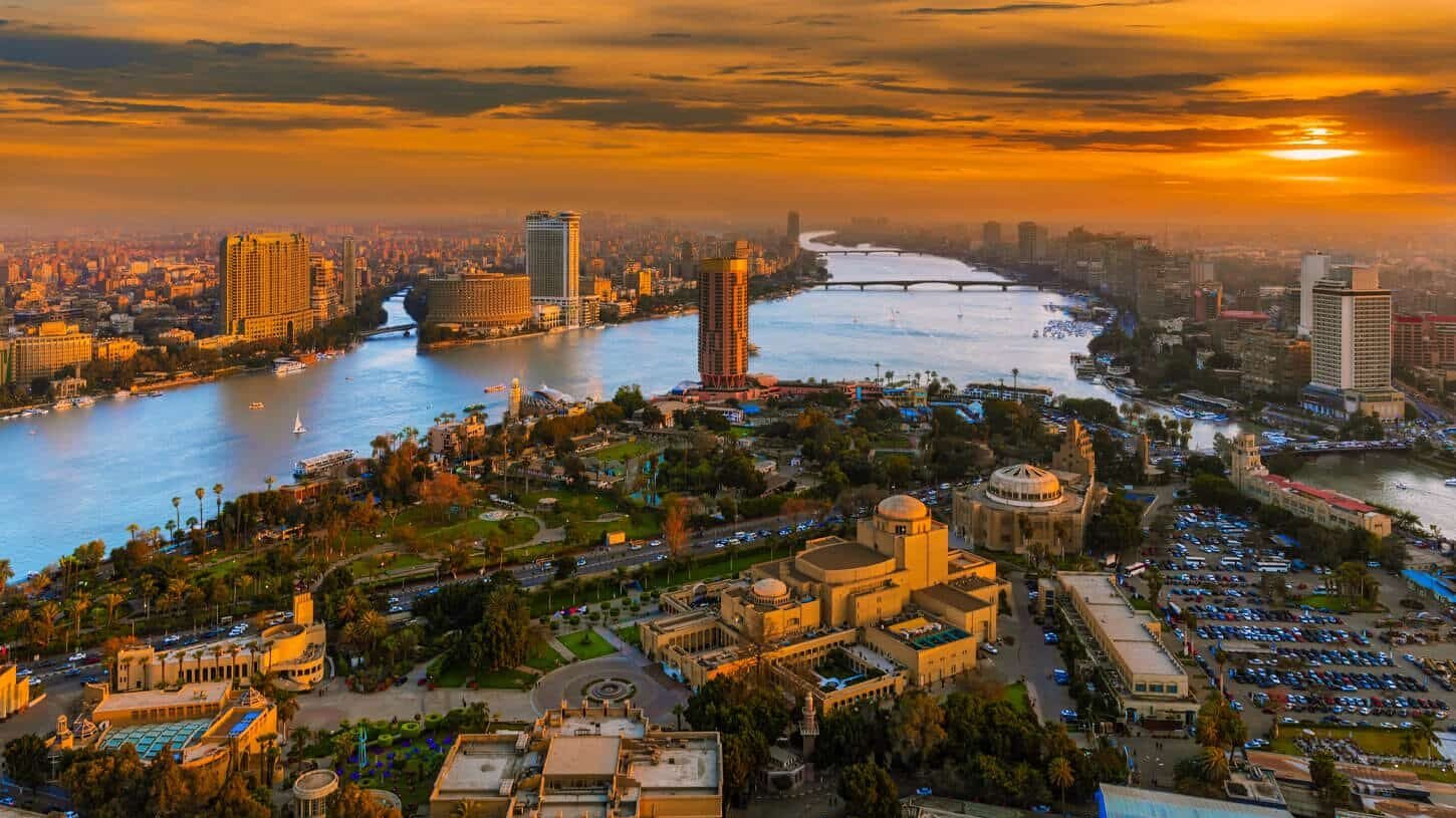 Vista aérea de El Cairo al atardecer con un cielo cálido y la silueta de la ciudad.