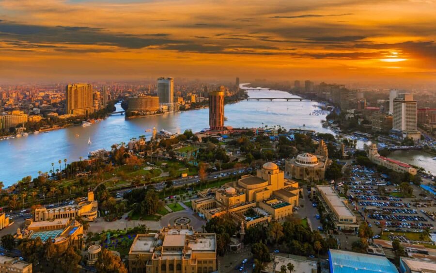 Vista aérea de El Cairo al atardecer con un cielo cálido y la silueta de la ciudad.