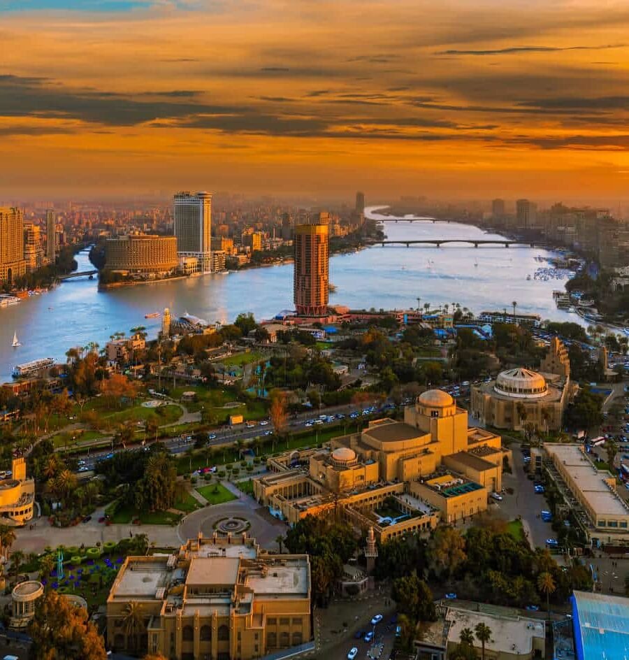 Vista aérea de El Cairo al atardecer con un cielo cálido y la silueta de la ciudad.