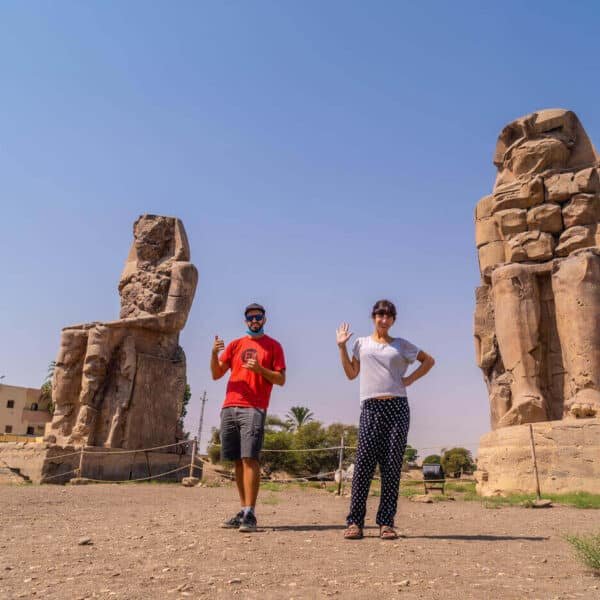 Pareja de turistas junto a las estatuas de Memnon en Luxor, Egipto.