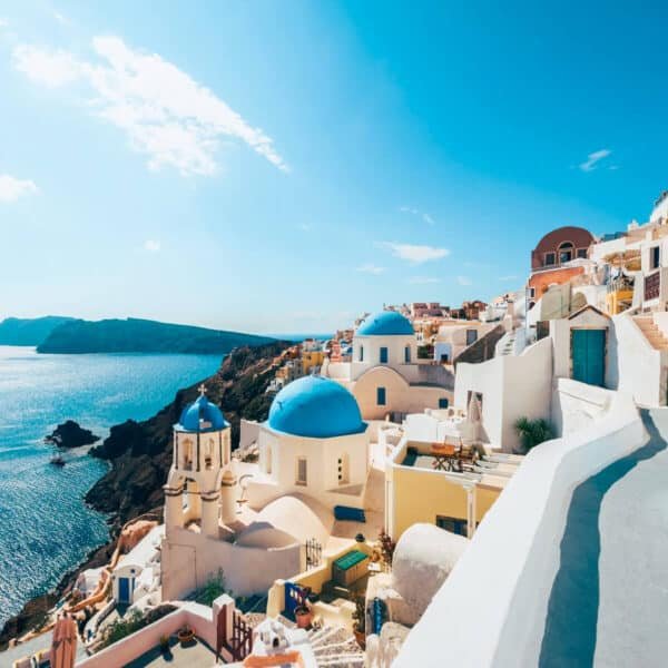 Vista panorámica de una ciudad costera en Grecia con casas blancas y mar azul.
