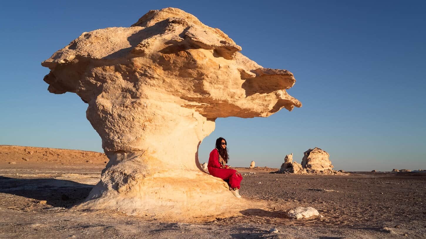 Chica de pie en las dunas blancas del Desierto Blanco bajo un cielo azul.