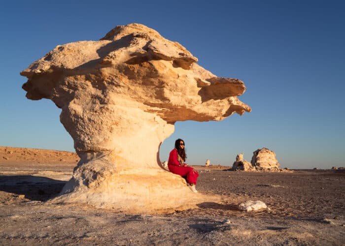 Chica de pie en las dunas blancas del Desierto Blanco bajo un cielo azul.