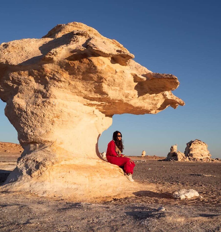Chica de pie en las dunas blancas del Desierto Blanco bajo un cielo azul.