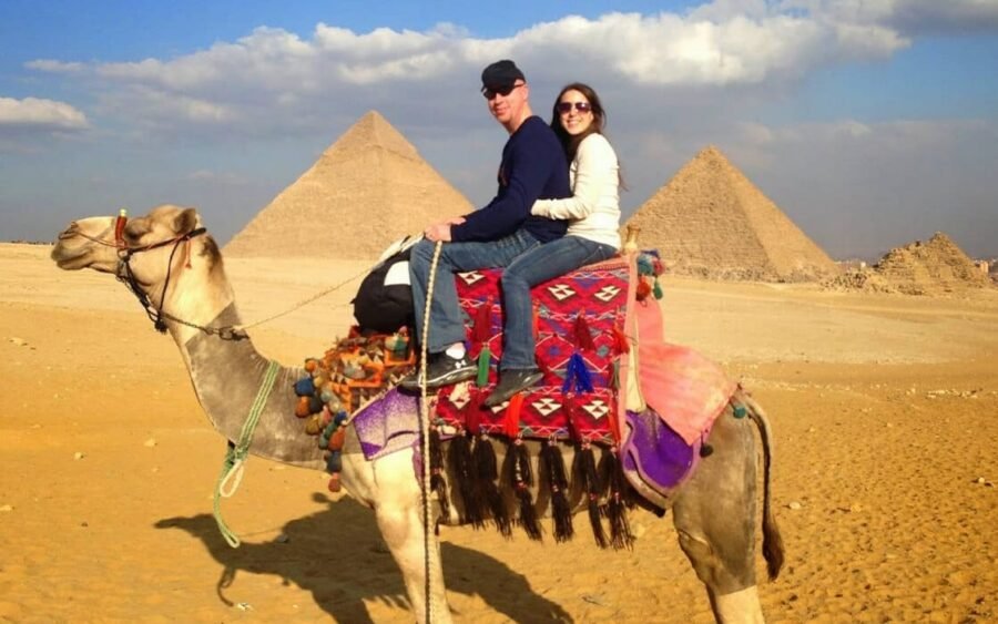 Pareja extranjera montando un camello cerca de las pirámides de Giza.