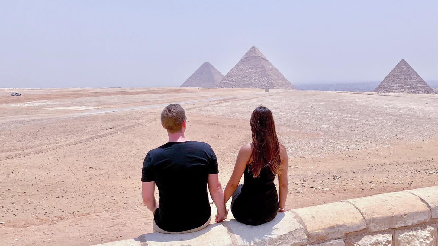 Pareja frente a las majestuosas pirámides de Giza en Egipto.