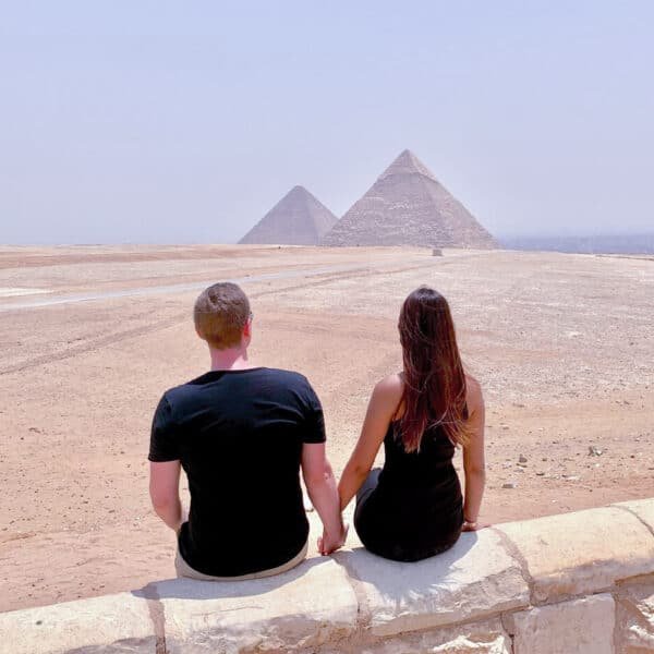 Pareja frente a las majestuosas pirámides de Giza en Egipto.