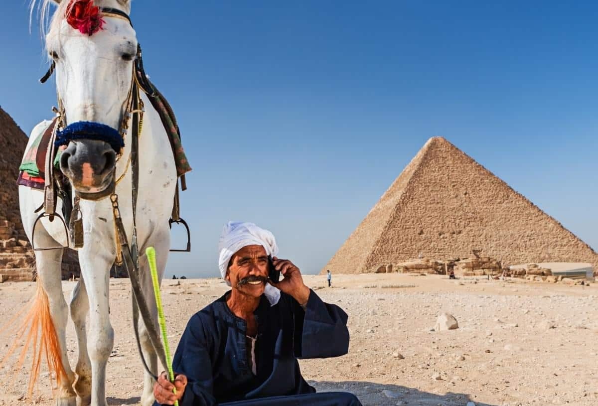 Hombre sentado frente a las pirámides de Egipto.