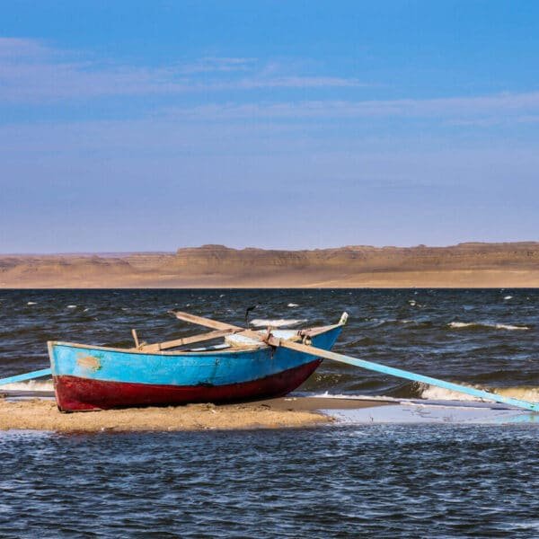Un barco colorido en la orilla del lago Qarun, en Fayoum, rodeado de naturaleza.