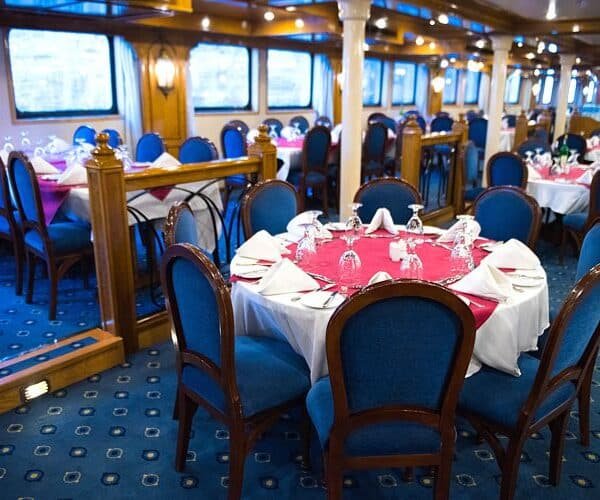 Sara disfrutando de un crucero por el Nilo con paisajes exuberantes y sitios históricos al fondo.