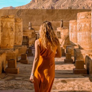 Turista extranjero junto a columnas de templo egipcio en un paisaje impresionante.