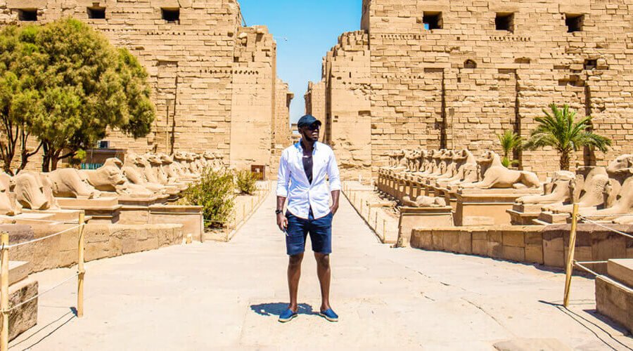 Hombre de pie en el Templo de Karnak, destacando la arquitectura antigua y majestuosa.