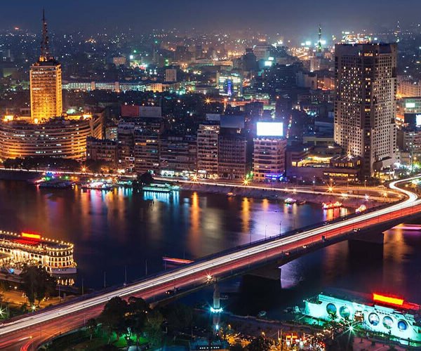 Vista nocturna de El Cairo con el horizonte iluminado y vibrante.