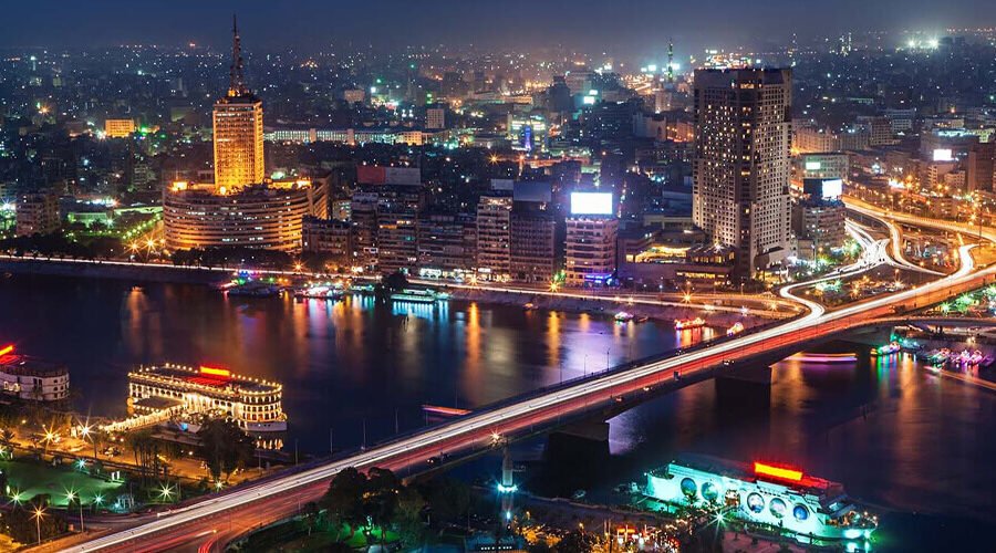 Vista nocturna de El Cairo con el horizonte iluminado y vibrante.