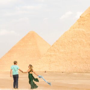 Pareja sonriendo frente a las pirámides de Egipto.