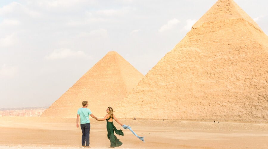Pareja sonriendo frente a las pirámides de Egipto.
