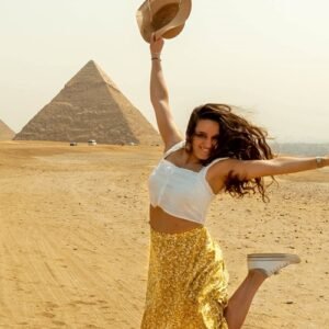 Turista extranjera saltando alegremente frente a las pirámides de Egipto.