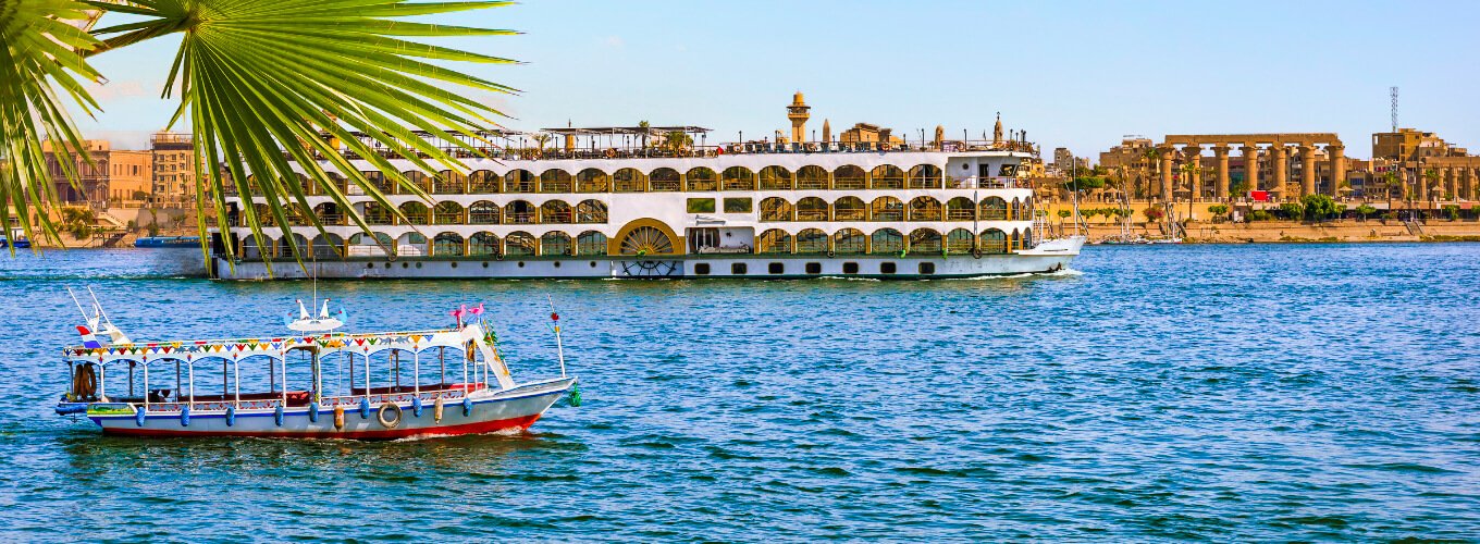Vista del Nilo y la ciudad de Luxor al atardecer con colores vibrantes.